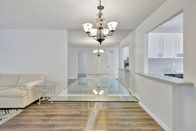 dining area featuring a textured ceiling, an inviting chandelier, and dark wood-type flooring