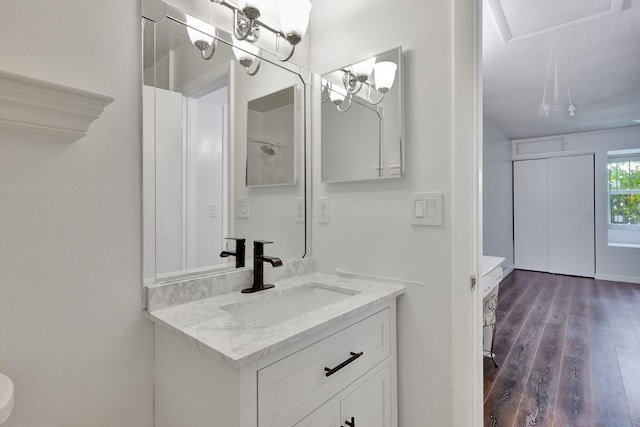 bathroom with a textured ceiling, wood-type flooring, and vanity