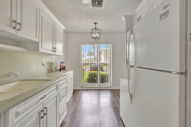 kitchen featuring white cabinets, decorative light fixtures, white fridge, and dark hardwood / wood-style flooring