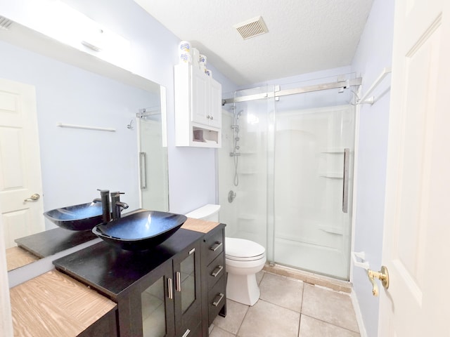 bathroom featuring vanity, tile patterned floors, a shower with shower door, toilet, and a textured ceiling