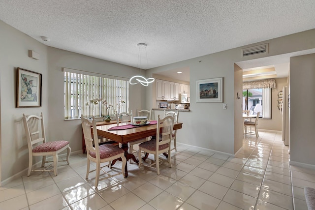 tiled dining room with a textured ceiling and a chandelier