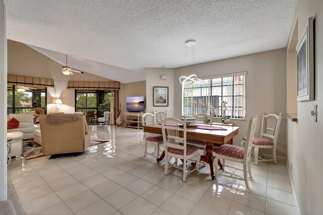 dining room featuring light tile patterned floors, vaulted ceiling, ceiling fan with notable chandelier, and a textured ceiling