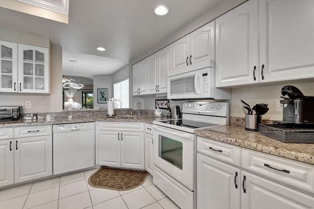 kitchen with white cabinets, light tile patterned flooring, light stone counters, and white appliances