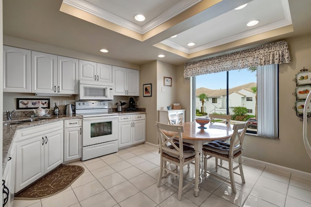 kitchen featuring crown molding, white appliances, sink, a tray ceiling, and white cabinetry