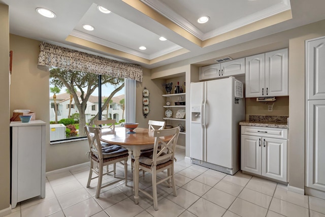 dining area featuring crown molding, a tray ceiling, and light tile patterned floors