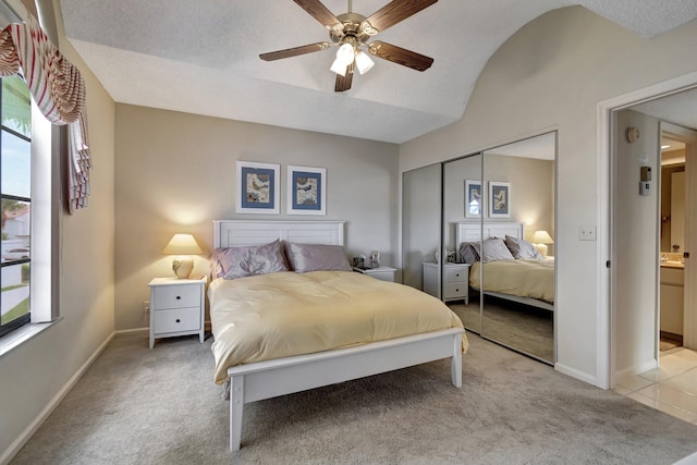 carpeted bedroom featuring ceiling fan, ensuite bath, a textured ceiling, and a closet