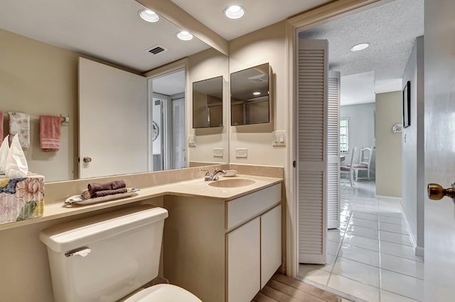 bathroom with a textured ceiling, toilet, tile patterned floors, and vanity