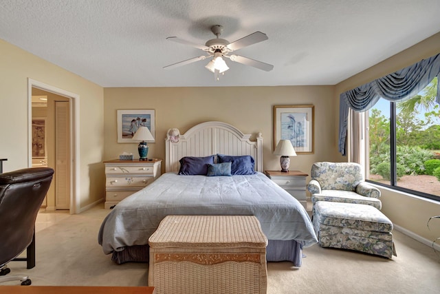 carpeted bedroom featuring ceiling fan and a textured ceiling