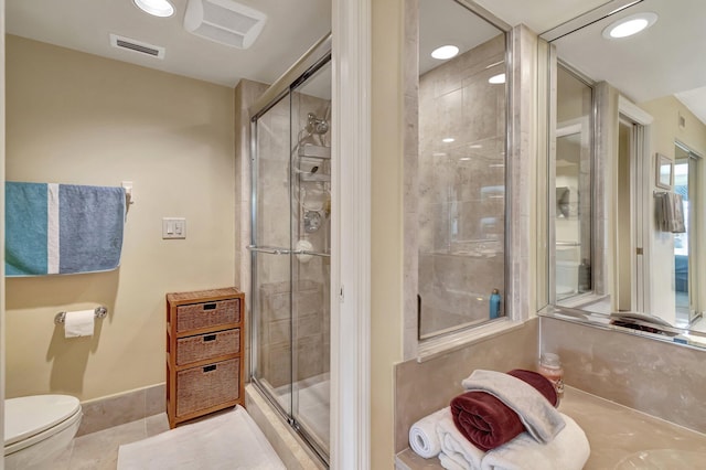 bathroom with an enclosed shower, toilet, and tile patterned flooring