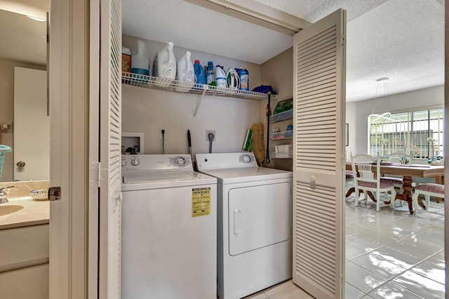 clothes washing area with light tile patterned floors, a textured ceiling, and washer and dryer