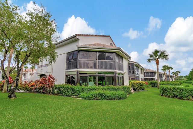 rear view of property with a lawn and a sunroom