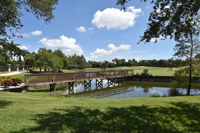 view of dock with a water view and a yard