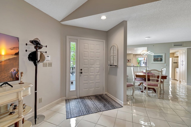 foyer entrance with light tile patterned flooring, a textured ceiling, and lofted ceiling