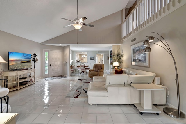 tiled living room with ceiling fan and high vaulted ceiling