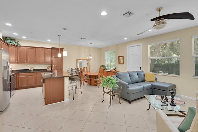 kitchen featuring ceiling fan with notable chandelier, a kitchen bar, plenty of natural light, and a center island with sink