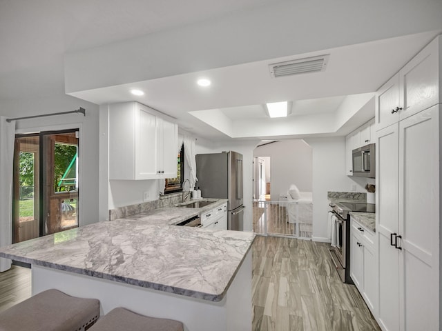 kitchen with white cabinets, a kitchen breakfast bar, kitchen peninsula, and appliances with stainless steel finishes