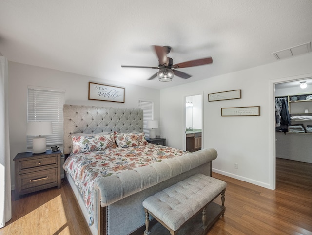 bedroom with ceiling fan, dark hardwood / wood-style flooring, a walk in closet, and a closet