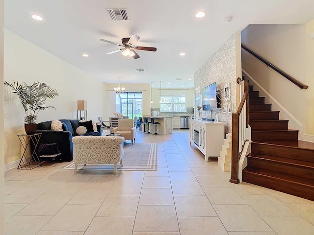 tiled living room with ceiling fan with notable chandelier