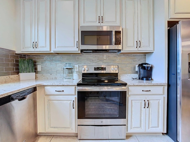 kitchen featuring appliances with stainless steel finishes, light tile patterned floors, tasteful backsplash, and light stone countertops