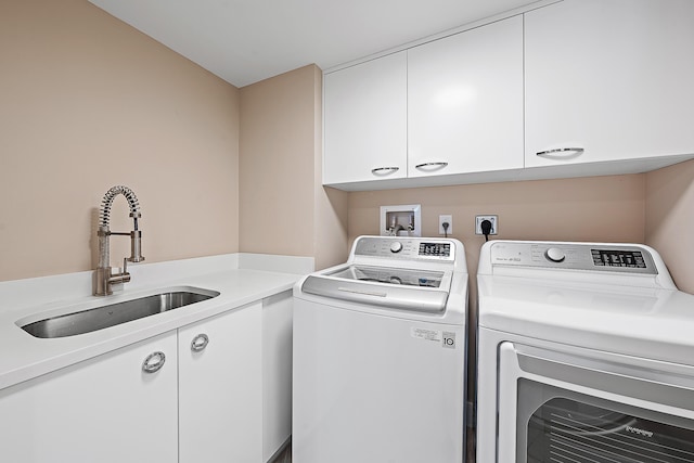 clothes washing area with cabinets, washer and clothes dryer, and sink