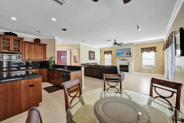 tiled dining room with ceiling fan, crown molding, sink, and a textured ceiling