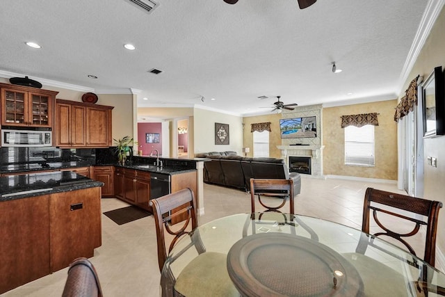 kitchen featuring ceiling fan, a large fireplace, sink, black dishwasher, and kitchen peninsula