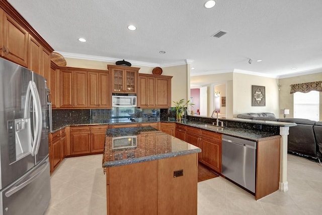 kitchen with light tile patterned flooring, appliances with stainless steel finishes, dark stone countertops, sink, and kitchen peninsula