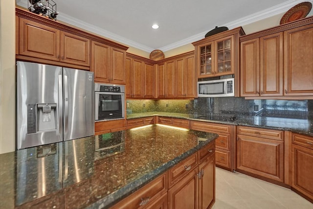 kitchen featuring stainless steel appliances, light tile patterned floors, dark stone counters, crown molding, and decorative backsplash