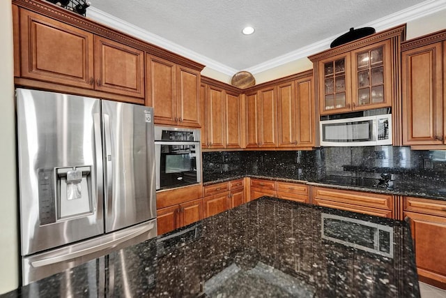 kitchen featuring appliances with stainless steel finishes, dark stone counters, ornamental molding, and tasteful backsplash