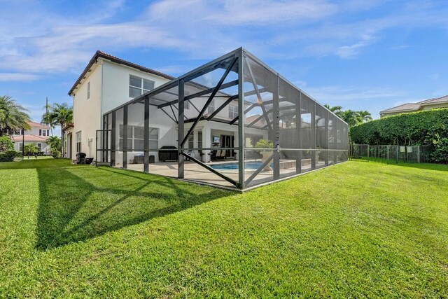 rear view of property featuring a lawn, glass enclosure, and a patio