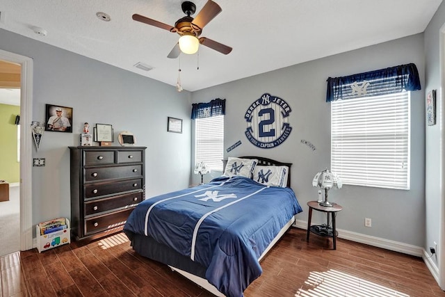 bedroom featuring dark hardwood / wood-style floors, ceiling fan, and multiple windows