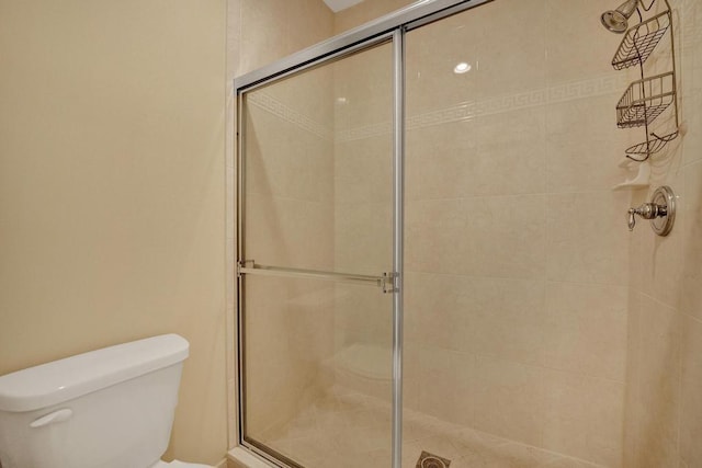 bathroom featuring a shower with door and toilet