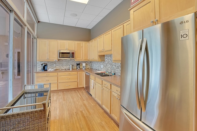 kitchen featuring sink, a drop ceiling, stainless steel appliances, light brown cabinetry, and light wood-type flooring