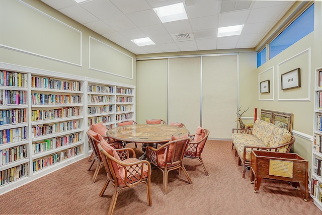 dining area with a paneled ceiling and carpet