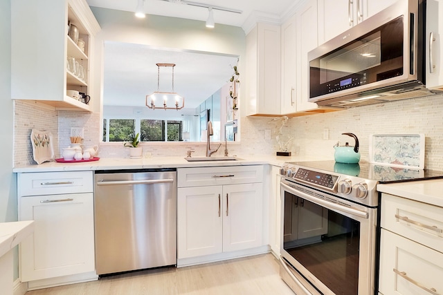 kitchen with track lighting, white cabinets, sink, decorative backsplash, and stainless steel appliances