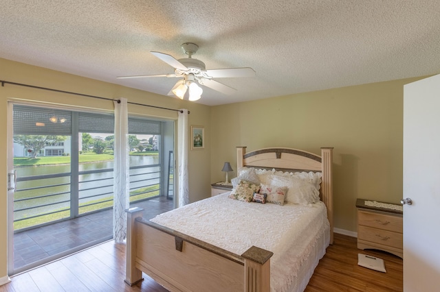 bedroom with ceiling fan, access to outside, multiple windows, and hardwood / wood-style flooring