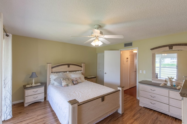 bedroom featuring a closet, a textured ceiling, hardwood / wood-style floors, and ceiling fan