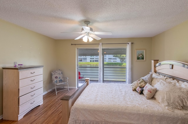 bedroom with ceiling fan, a textured ceiling, access to outside, and hardwood / wood-style floors