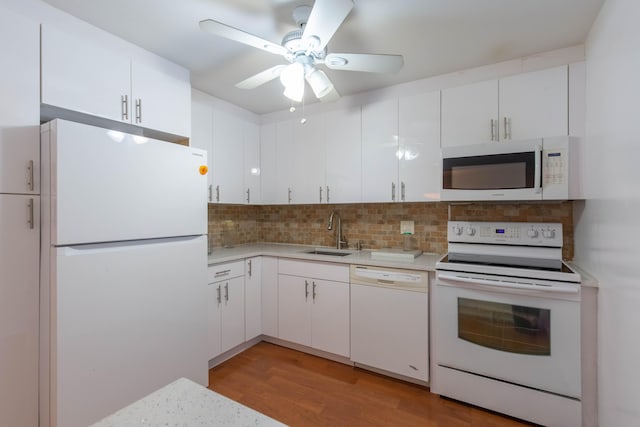 kitchen featuring white appliances, white cabinets, light wood-type flooring, sink, and backsplash