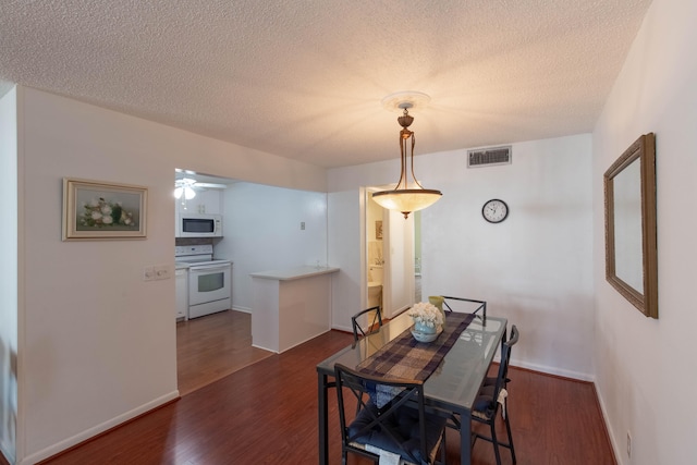 dining area with a textured ceiling, dark wood-type flooring, and ceiling fan