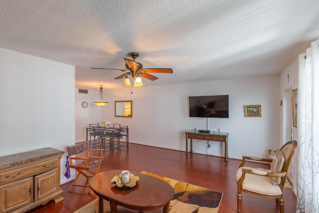 living room with ceiling fan, a textured ceiling, and dark hardwood / wood-style floors