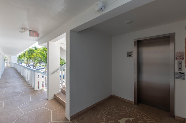 view of exterior entry with a balcony and elevator