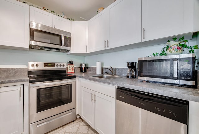 kitchen featuring appliances with stainless steel finishes, white cabinetry, and sink