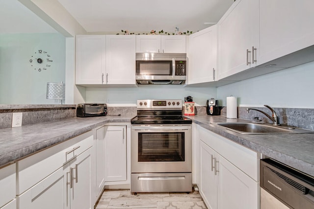 kitchen with appliances with stainless steel finishes, sink, white cabinets, and light hardwood / wood-style floors