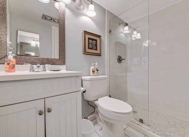 bathroom featuring vanity, toilet, decorative backsplash, and a tile shower