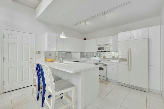 kitchen featuring kitchen peninsula, a kitchen breakfast bar, white appliances, pendant lighting, and white cabinetry