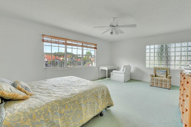 bedroom featuring a textured ceiling, ceiling fan, light carpet, and multiple windows