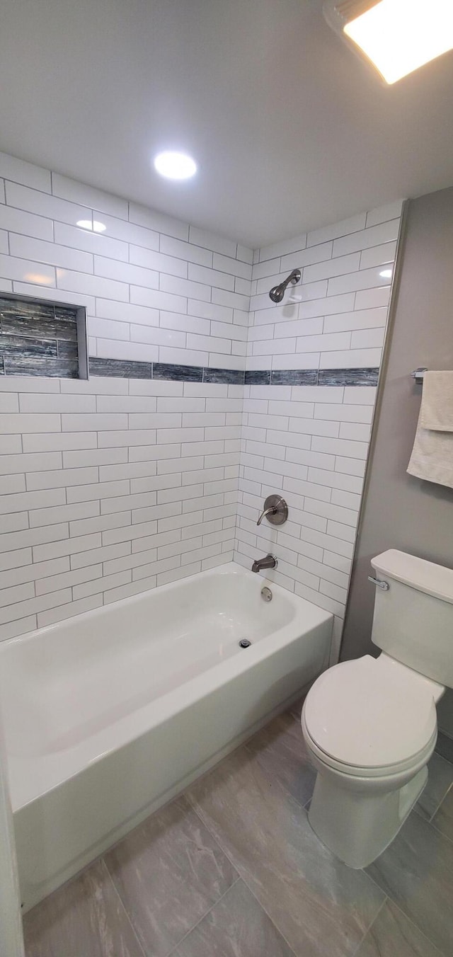 bathroom with tiled shower / bath combo, tile patterned flooring, and toilet