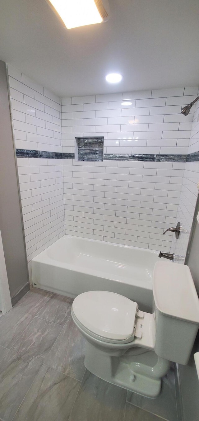 bathroom featuring toilet, tile patterned floors, and tiled shower / bath combo