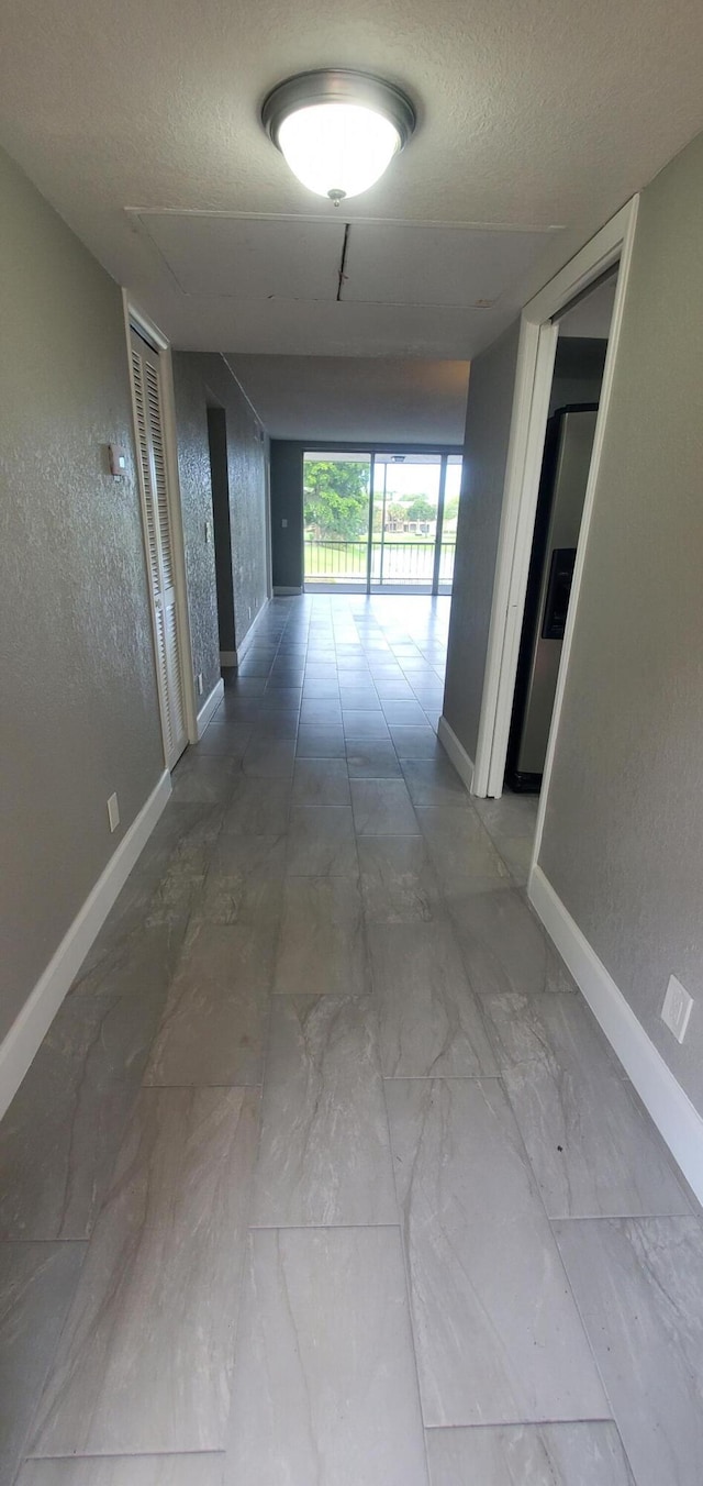 corridor with a textured ceiling and tile patterned flooring